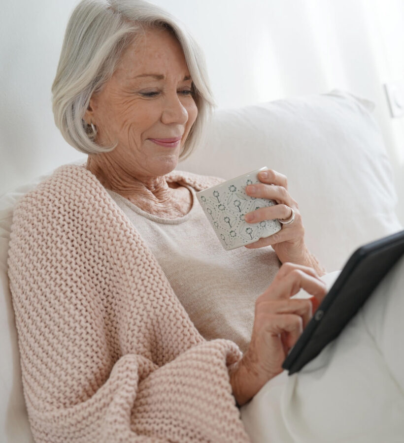 Elderly woman enjoying a cup of tea and going on her iPad