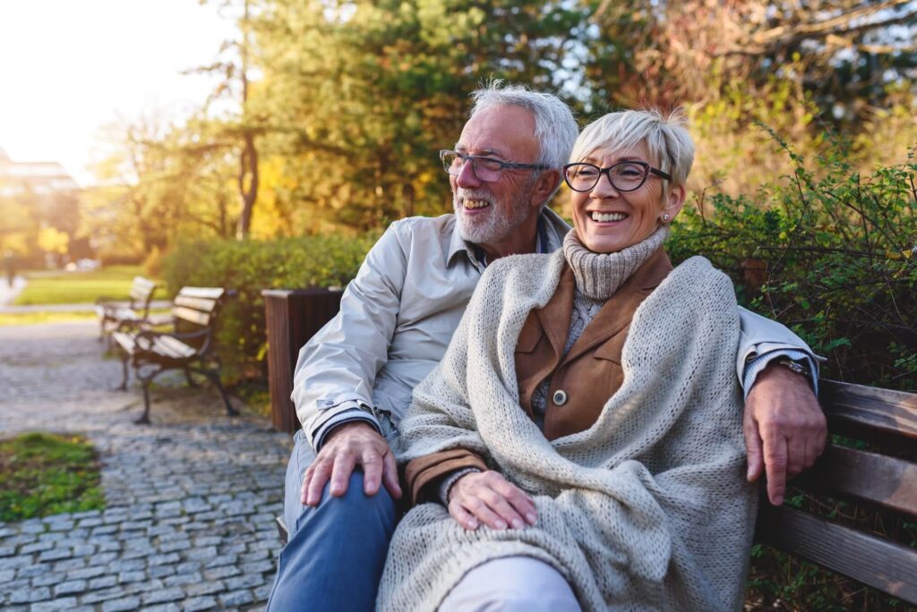 Cheerful couple sitting on a bench in nature together