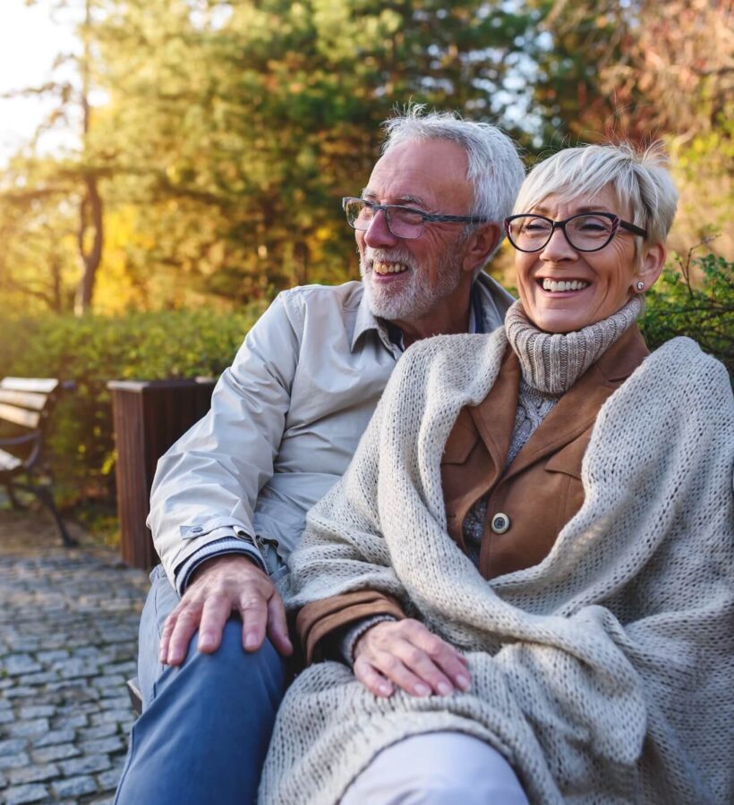 Cheerful couple sitting on a bench in nature together