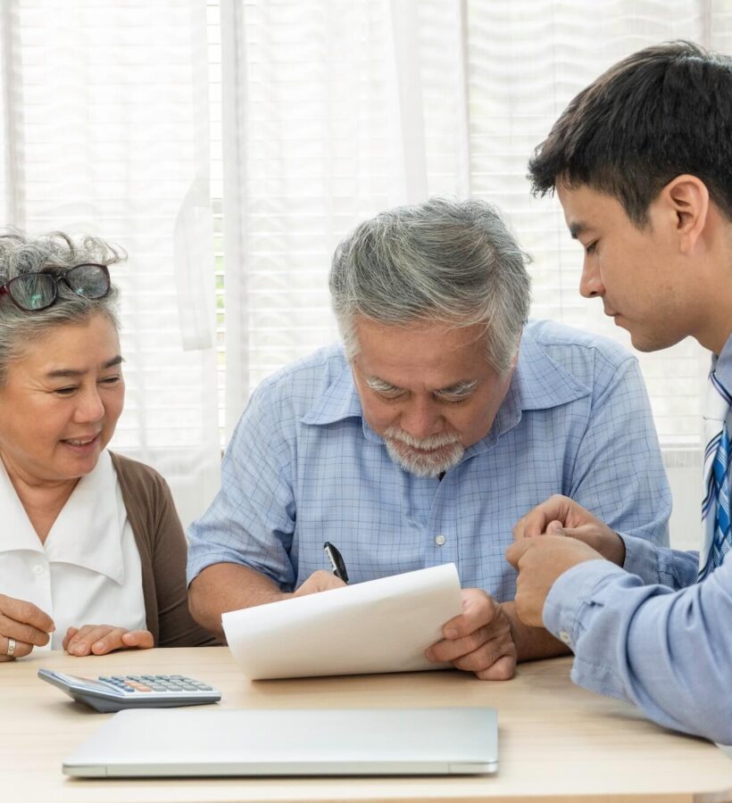 Elderly couple signing paperwork with their advisor